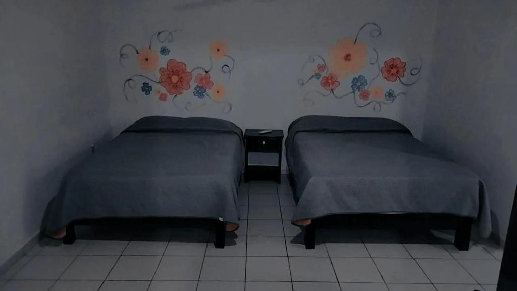duas camas num pequeno quarto com flores na parede em Casa la Conchita em San Luis Potosí