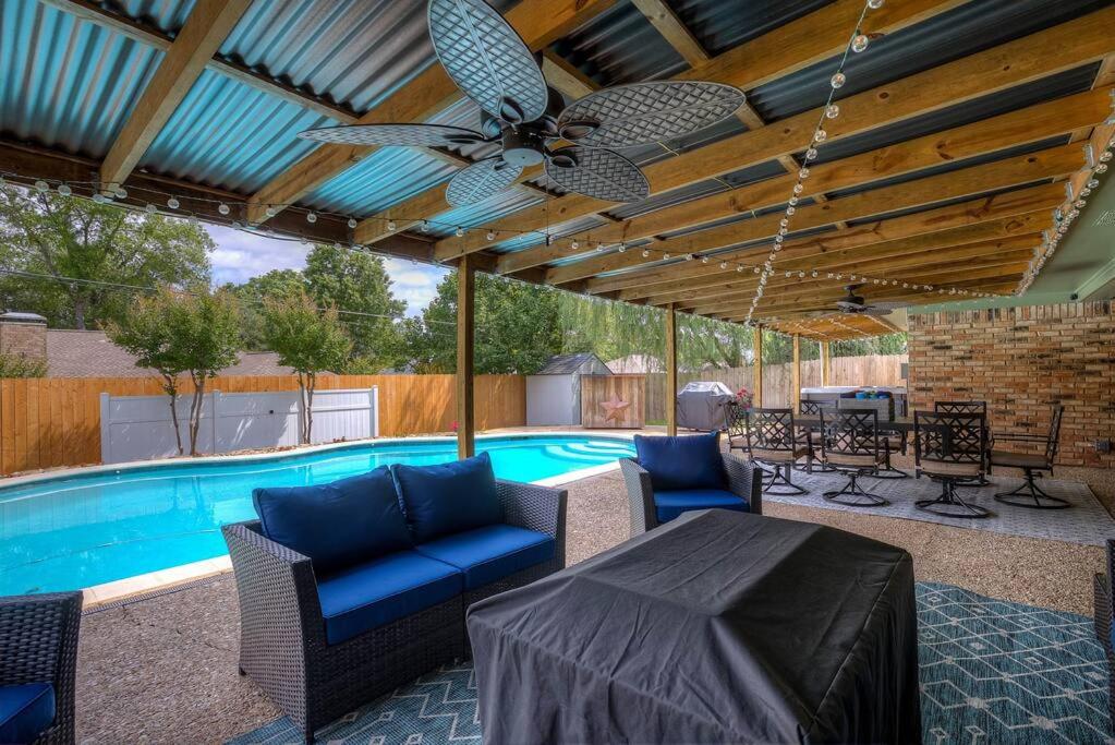 um pátio com uma ventoinha de tecto e uma piscina em Beautiful 4 bedroom home with Pool, Hot Tub & More em Tyler