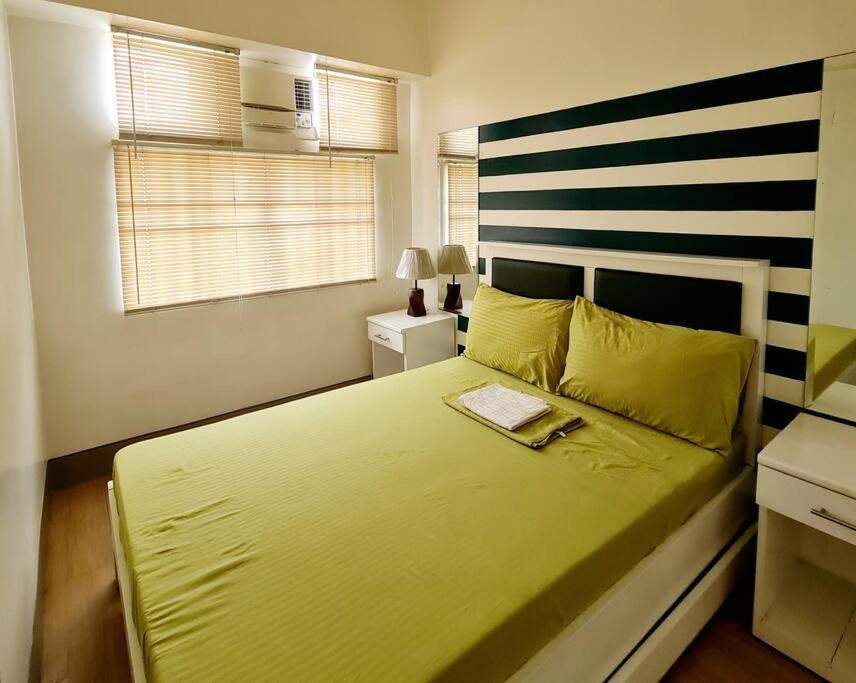 een slaapkamer met een groen bed met een gestreept hoofdeinde bij Modern & Spacious 2BR Condo with Netflix & Pool Acess in San Juan Manila in Manilla