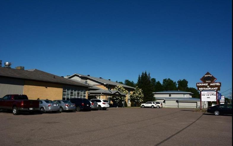 um parque de estacionamento com carros estacionados em frente a um edifício em Bear's den Lounge and Motel em Deep River