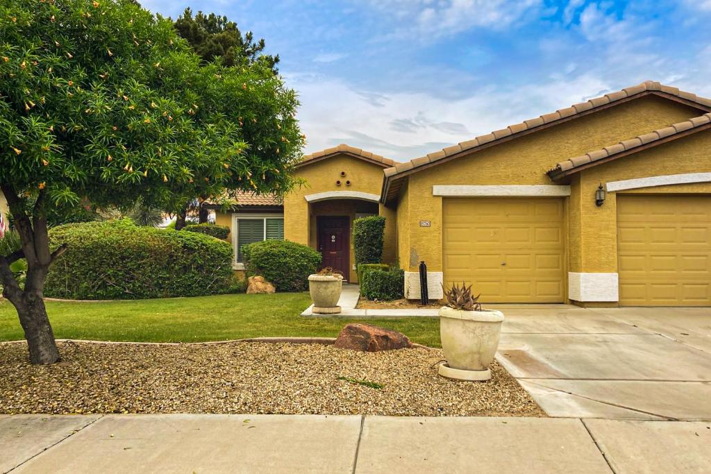 a yellow house with a tree and a driveway at Good Memories in Goodyear in Goodyear