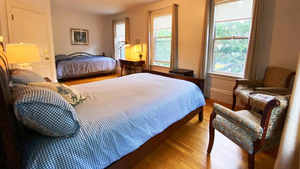 a bedroom with a bed and a chair and two windows at Ginkgo House on Harvard in Cambridge