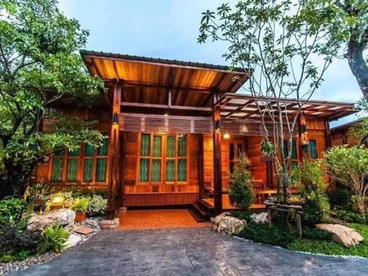 une maison en bois avec un chemin en face de celle-ci dans l'établissement Areeya phubeach resort wooden house, à Ban Chong Phli