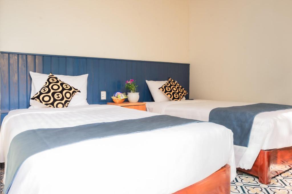 two beds in a room with white and blue at Catba Papillon Garden Bungalows & Resort in Cat Ba