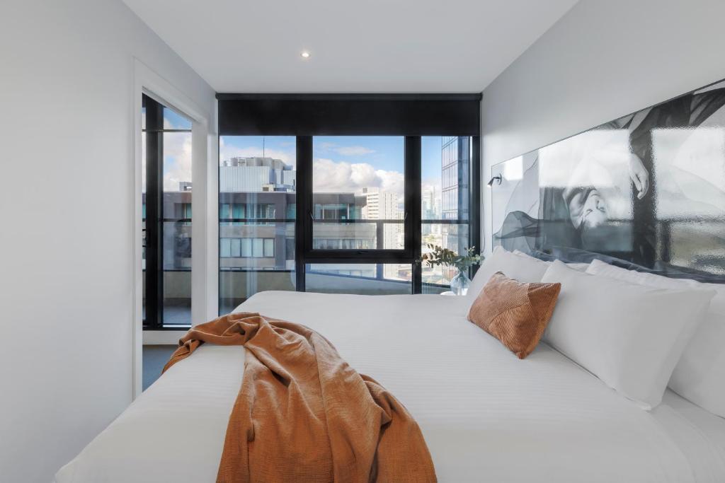 a bedroom with a white bed with a large window at Imagine Southbank in Melbourne