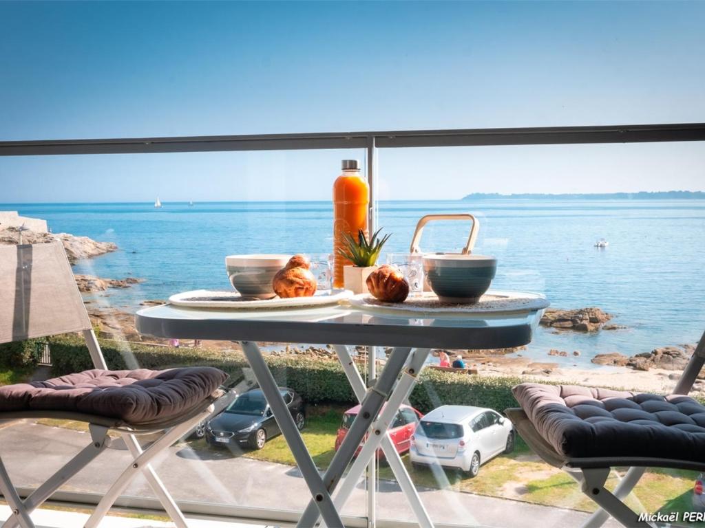 - une table avec de la nourriture sur le balcon donnant sur l'eau dans l'établissement Ploemeur - Appartement 3 pièces avec balcon, ascenseur et WIFI près de la plage - FR-1-349-90, à Ploemeur