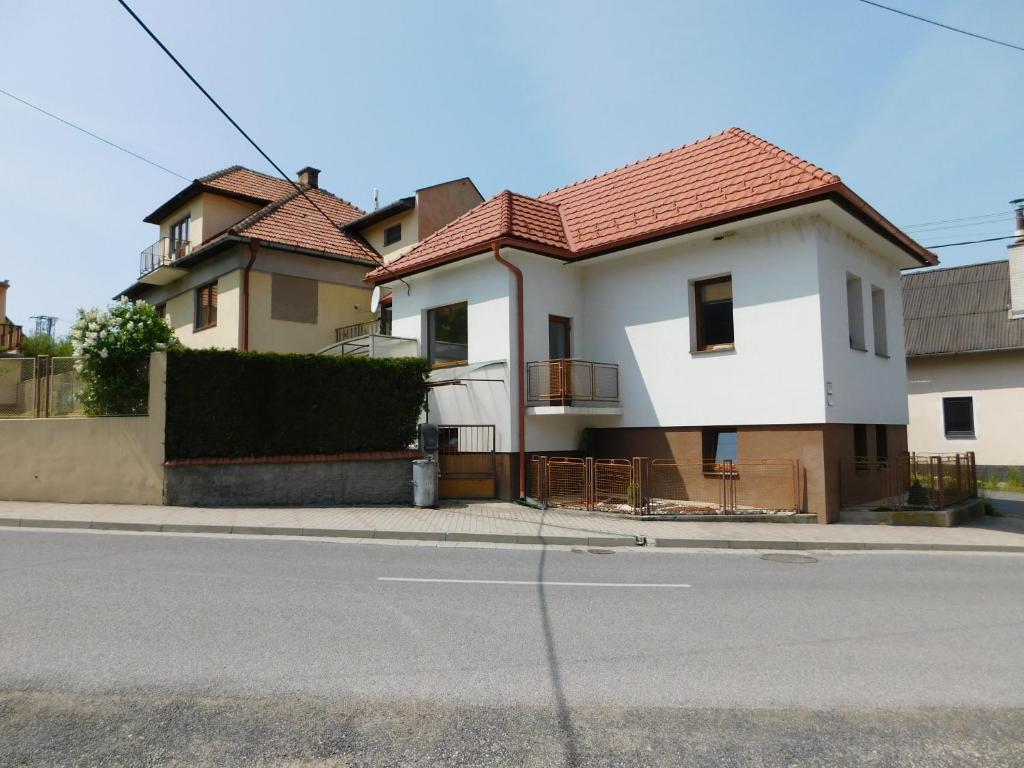 una casa blanca con techo rojo en una calle en Apartmán Magdaléna, en Závažná Poruba