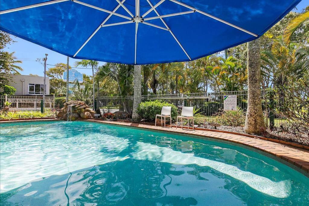 a large pool with a blue umbrella and chairs at Seabreeze at Silver Sands Hervey Bay in Hervey Bay
