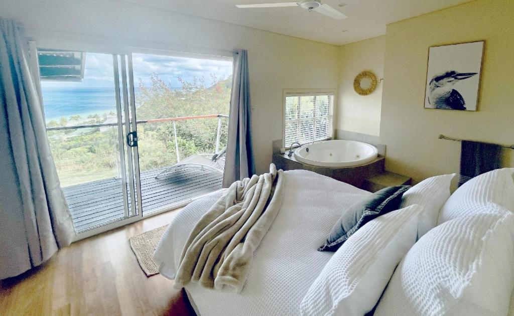 a bedroom with a bed and a tub and a window at Shore Bird On Moreton in Tangalooma