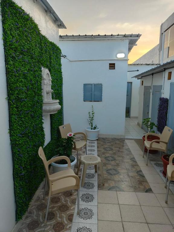 un patio con sedie, tavoli e una parete verde di استراحة a Al Maraghah