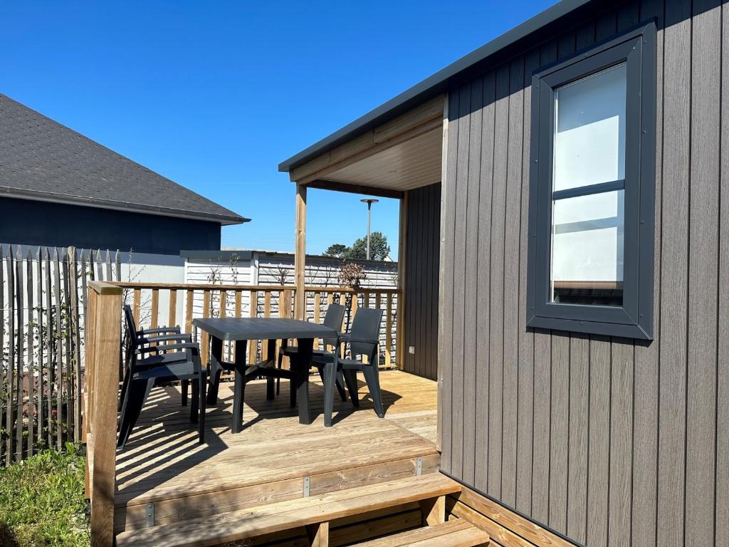 une terrasse avec une table et des chaises sur une maison dans l'établissement Mobil-home de Grand Confort à 200m de la plage avec piscine chauffée, 2 chambres, parking, wifi inclus - FR-1-361A-44, à Jullouville