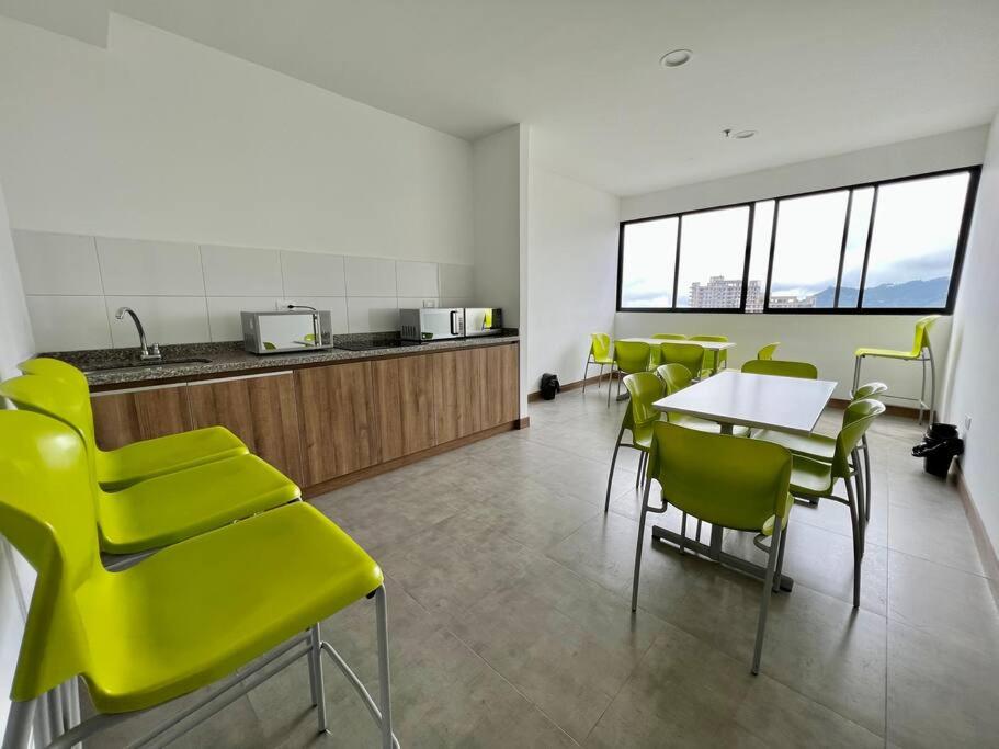 a room with yellow chairs and a table and a kitchen at Cama Queen, Vista a las Montañas in Manizales