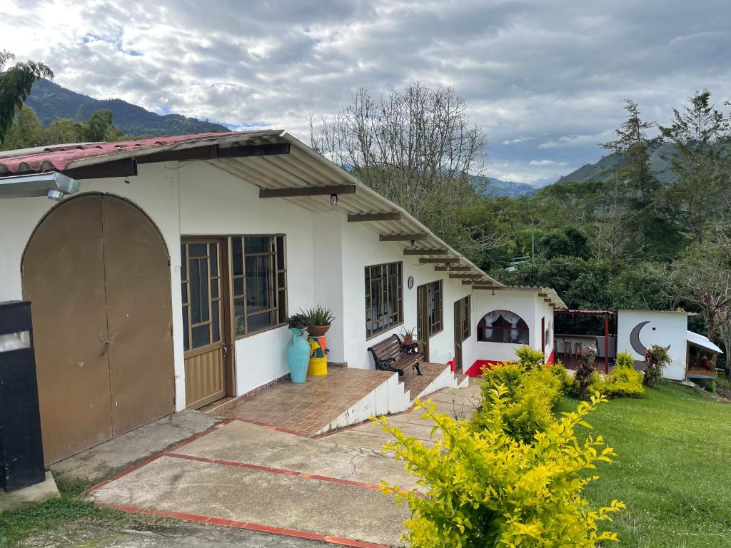 a small white house with a porch and a yard at Cabaña Campestre Miraluna in Choachí