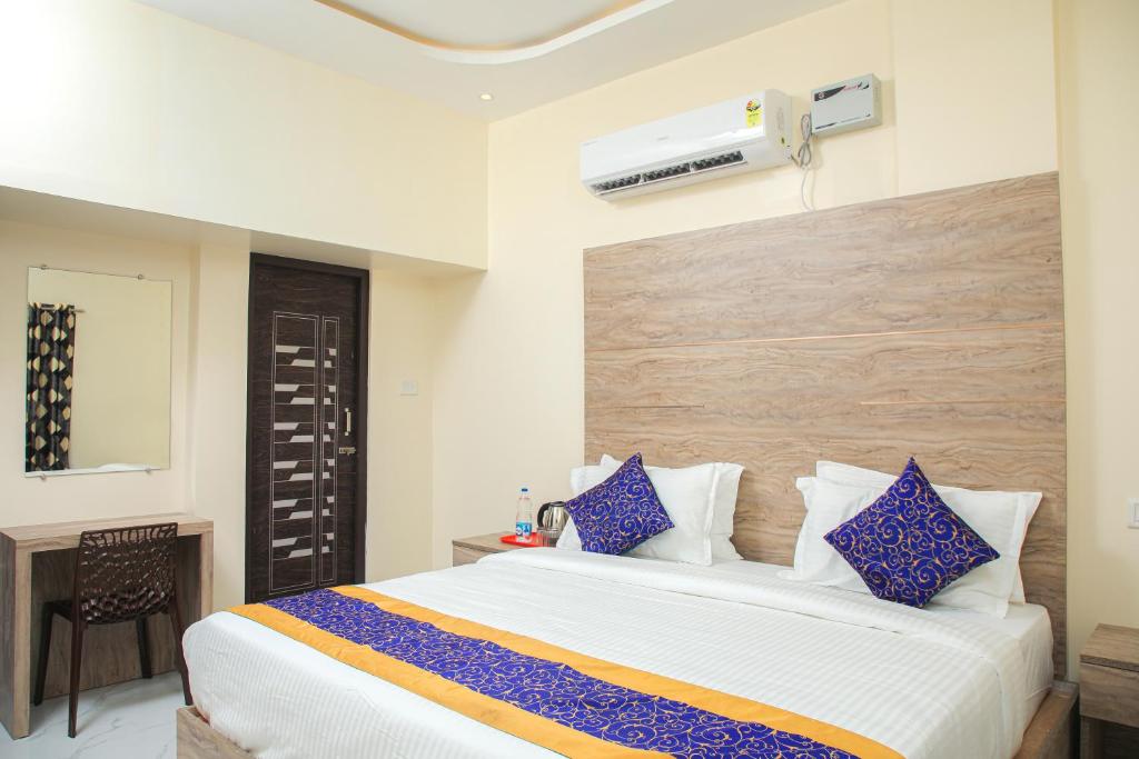 um quarto com uma grande cama branca com almofadas azuis em Redstone Service Apartment-TNagar Near USConsulate em Chennai