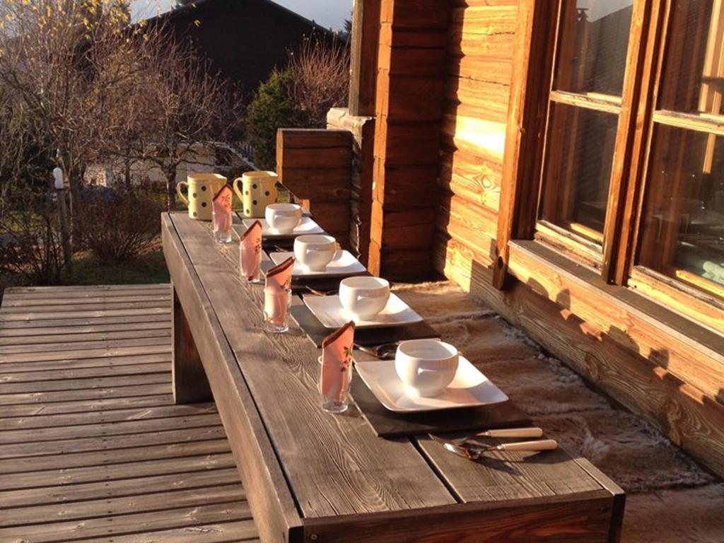 a wooden table with plates and cups on a deck at Chalet bois 9 pers, Grand confort, près pistes et commerces, Wi-Fi, Equipé, Parking, Non fumeur - FR-1-733-18 in Crest-Voland