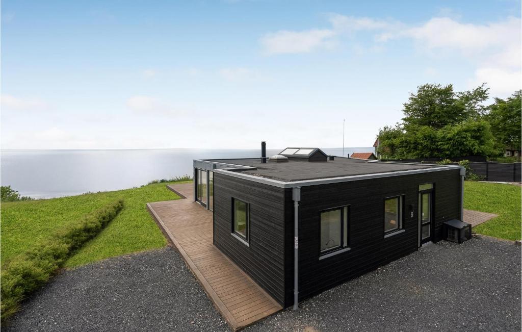 une petite maison noire sur une terrasse à côté d'une masse d'eau dans l'établissement 3 Bedroom Lovely Home In Haderslev, à Kelstrup