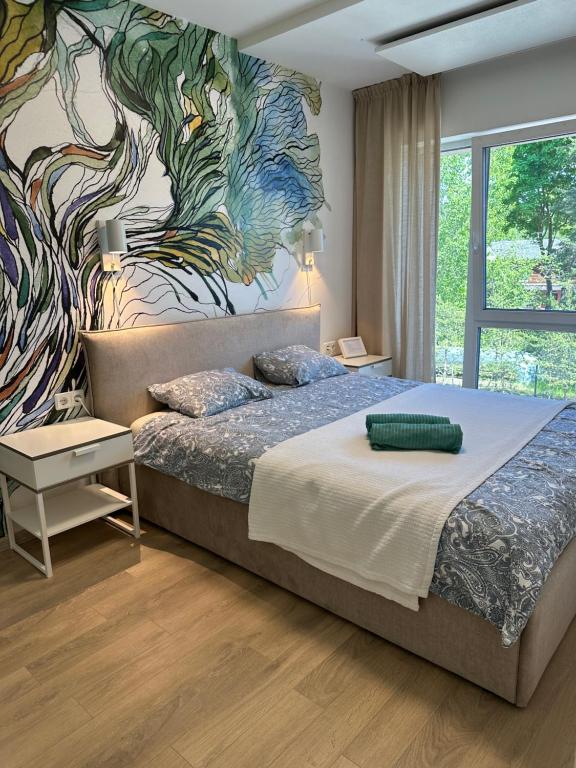 une chambre avec un grand lit avec un tableau au mur dans l'établissement Malūno Vilos 1M7, à Palanga