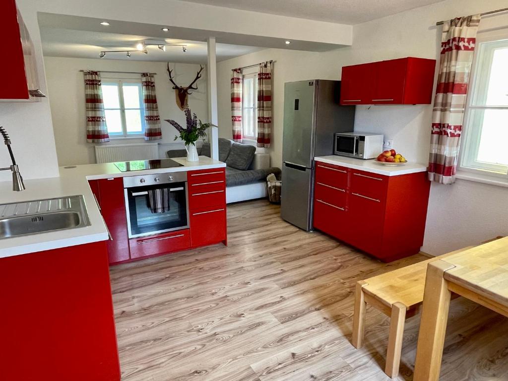 eine Küche mit roten Schränken und einem Tisch im Zimmer in der Unterkunft Lendorfer Cottage in Feldkirchen in Kärnten