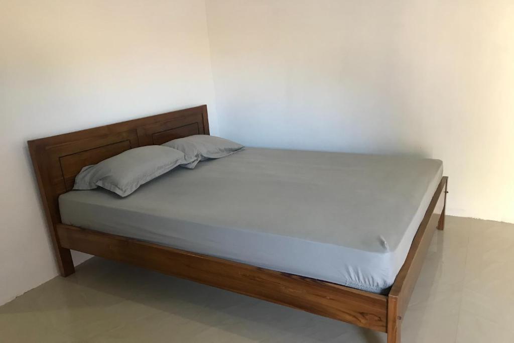 łóżko z drewnianą ramą i białą ścianą w obiekcie OYO 92603 Lidya Homestay w Labuan Bajo