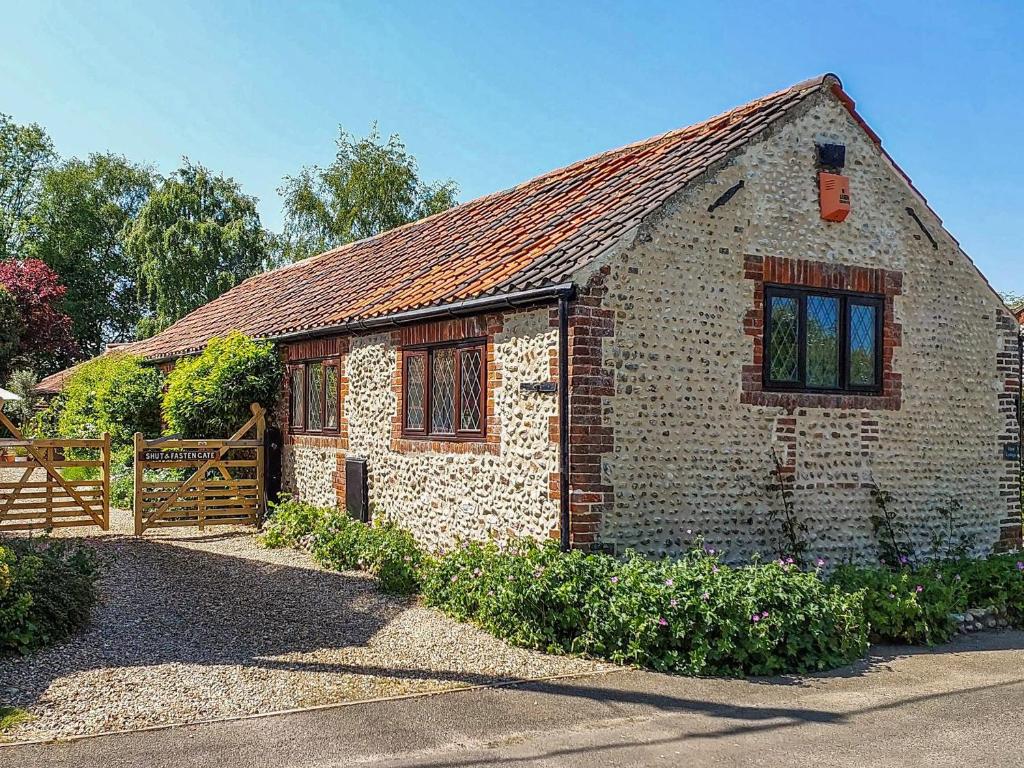 a small brick house with a wooden fence at Hunt Cottage in Sharrington