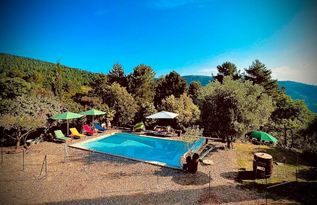 a swimming pool with chairs and umbrellas next to a mountain at Le Planzollais in Planzolles
