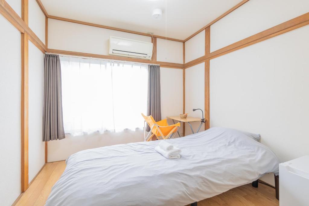 a bedroom with a white bed and a window at Wabi Sabi Hostel in Tokyo