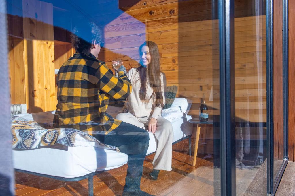 Ein Mann und eine Frau sitzen in einem Glasfenster in der Unterkunft Svaneti Сountryside 1 in Shkaleri