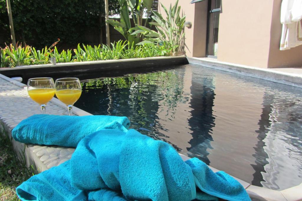 two glasses of wine and towels next to a swimming pool at Absolute Bosch Guest House in Stellenbosch