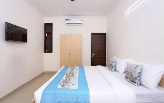 a bedroom with a large bed with a blue blanket at POP 81169H Sunview Stay in Gurgaon