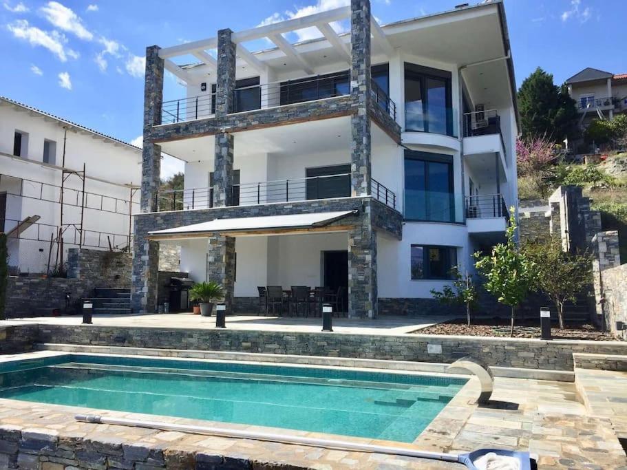 a house with a swimming pool in front of a building at Luxury Villa by the Sea in Volos