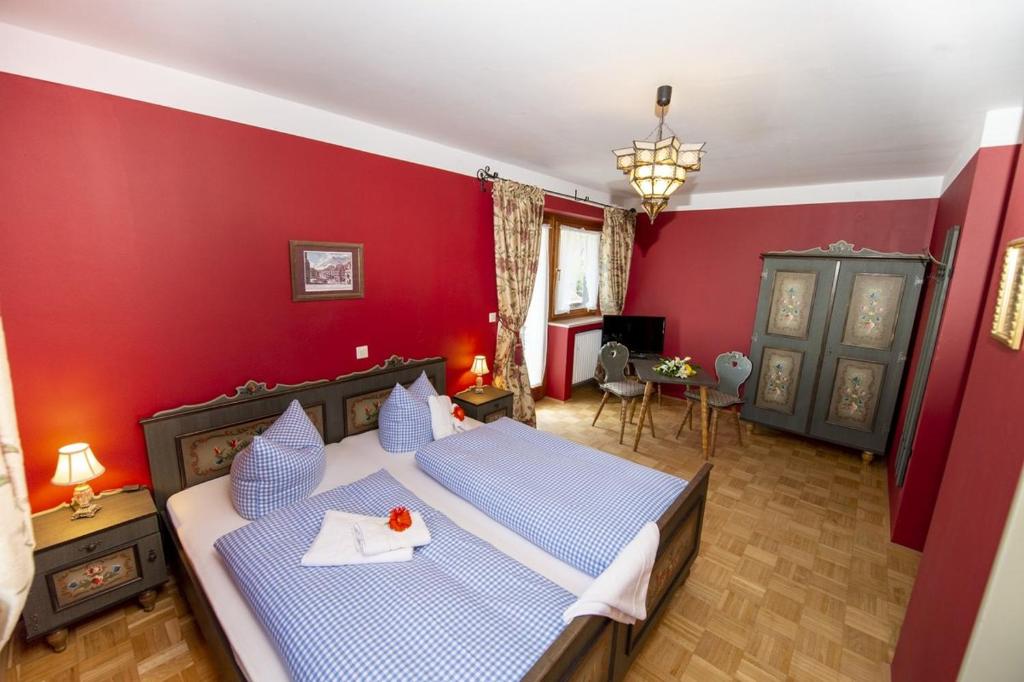 a bedroom with a blue bed with a red wall at Pension Maria in Antdorf