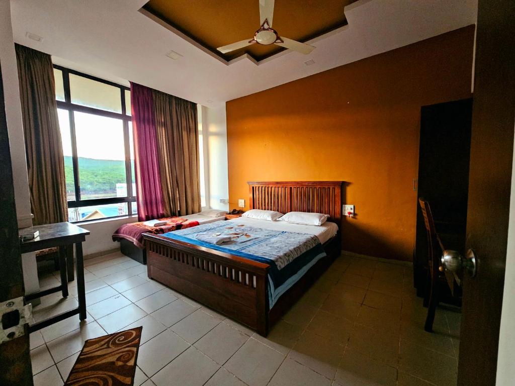 a bedroom with a bed and a large window at Suman Cottage & Bungalow in Mahabaleshwar
