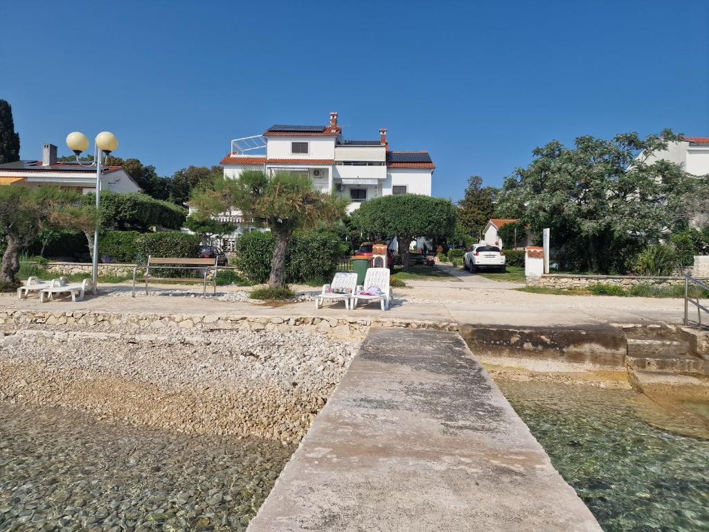 un par de sillas sentadas en una pasarela cerca del agua en Villa Katarina en Petrcane