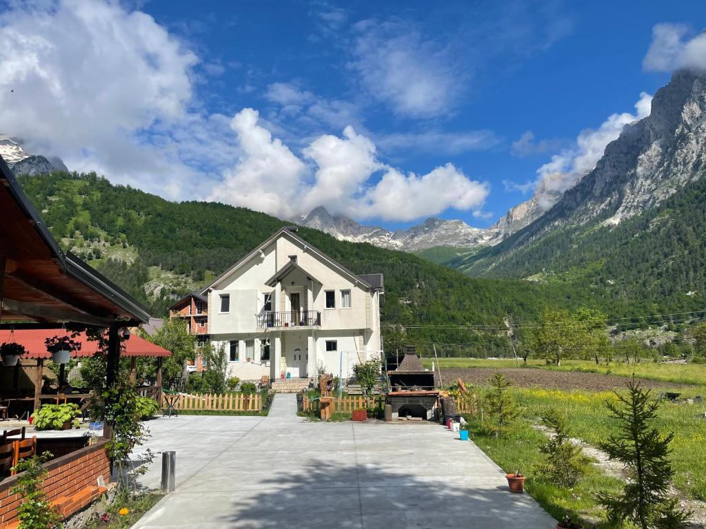 Une grande maison blanche avec des montagnes en arrière-plan dans l'établissement BUJTINA IZET SELIMAj, à Valbonë