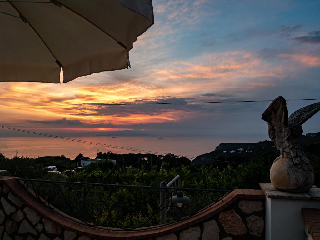 a view of a sunset from a balcony with an umbrella at Casa Astra in Anacapri