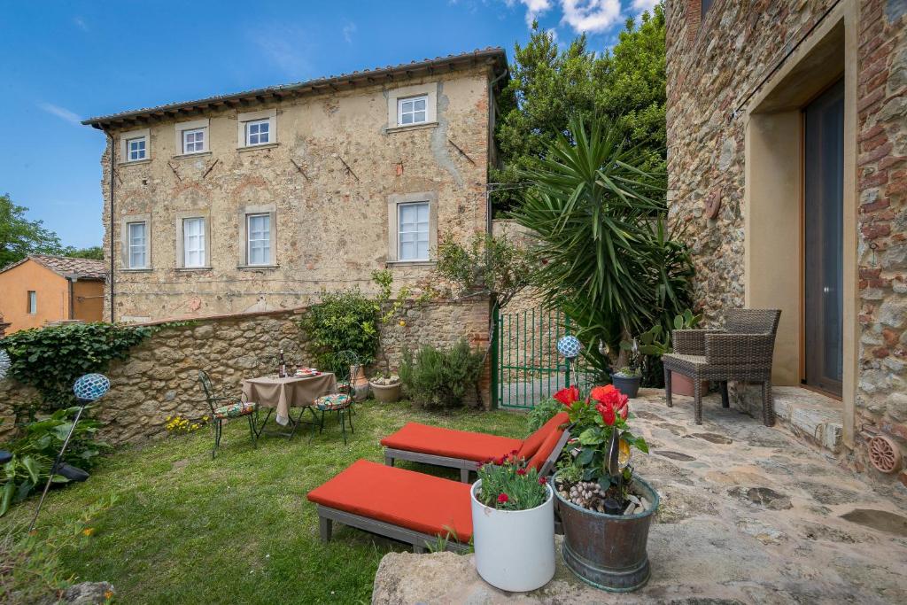 einen Garten mit Stühlen und Tischen sowie ein Gebäude in der Unterkunft La Stallina in Sant'Ermo