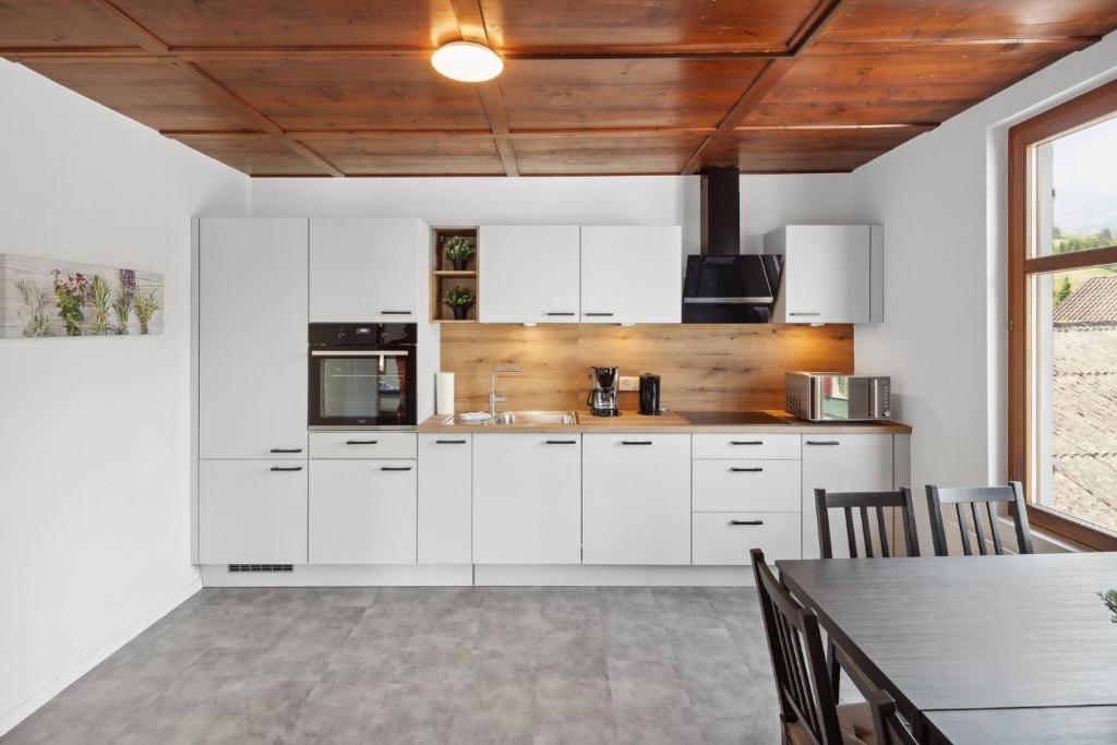 une cuisine avec des placards blancs et une table avec des chaises dans l'établissement FENUS Apartment mit traumhaftem Bergblick, à Grabs