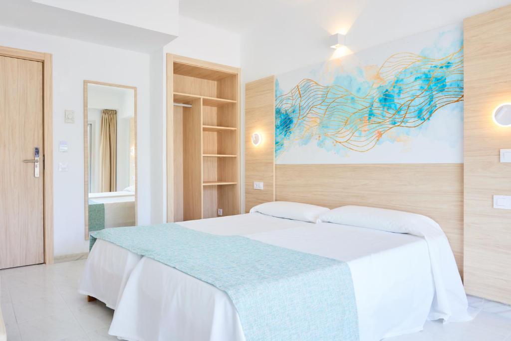 - une chambre avec un lit blanc et une peinture murale dans l'établissement Hostal Gami Adults Only, à Cala Ratjada