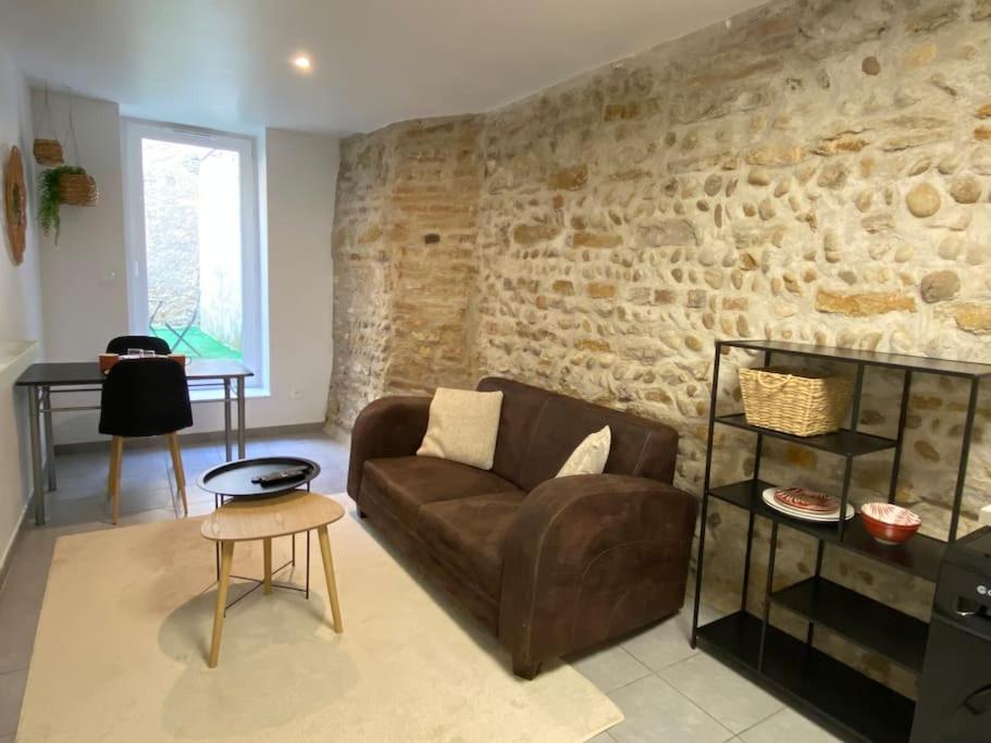 un salon avec un canapé et un mur en pierre dans l'établissement Vaste Appartement Rénové - Centre Ville, à Bourg-en-Bresse