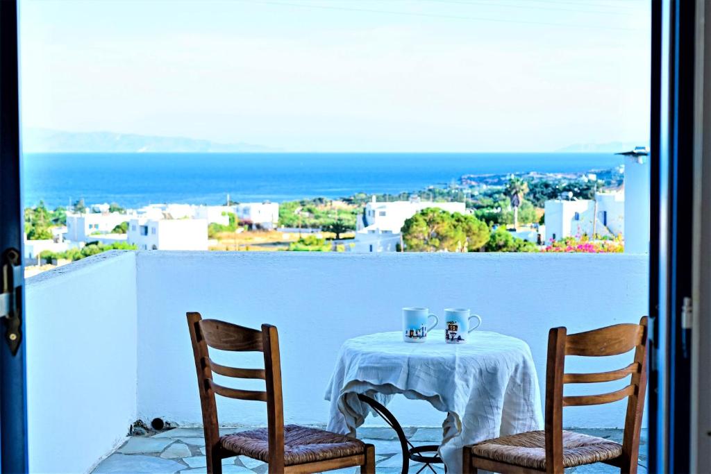 a table with two chairs and a view of the ocean at Cycladic Bliss - Uncovering Paros Seaview Gem in Drios