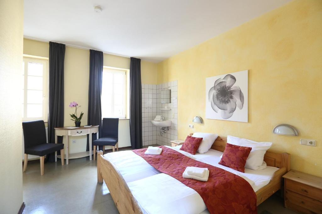 um quarto com uma cama grande, uma secretária e cadeiras em Kolping Hostel Trier im Warsberger Hof em Trier
