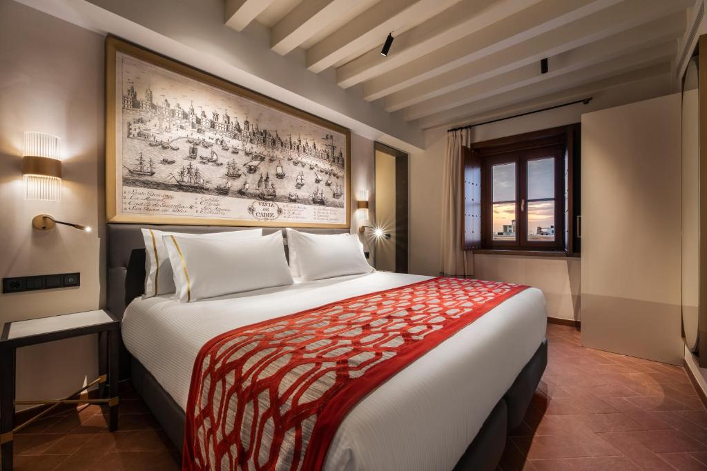 a hotel room with a large bed and a painting on the wall at Áurea Casa Palacio Sagasta by Eurostars Hotel Company in Cádiz