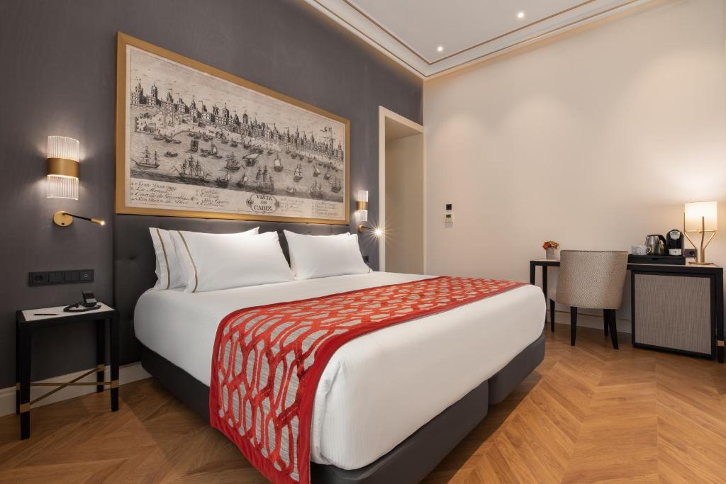a hotel room with a large bed and a table at Áurea Casa Palacio Sagasta by Eurostars Hotel Company in Cádiz