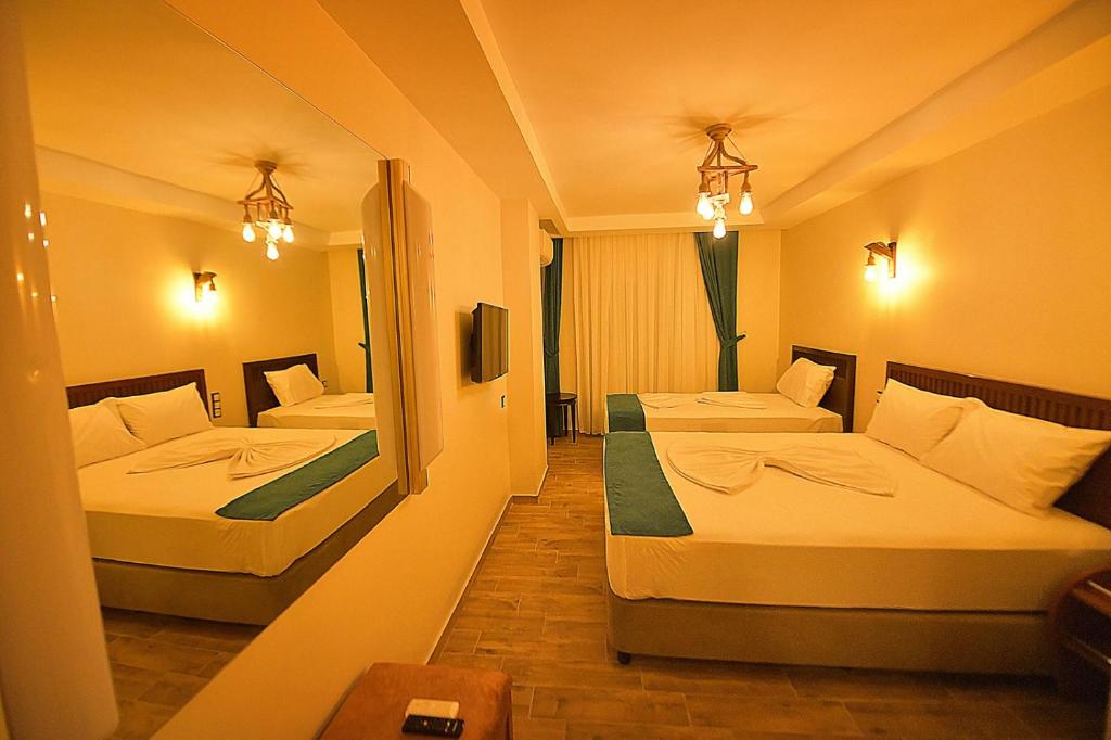 a hotel room with two beds and a mirror at MİDYAT LADİNOS OTEL in Midyat