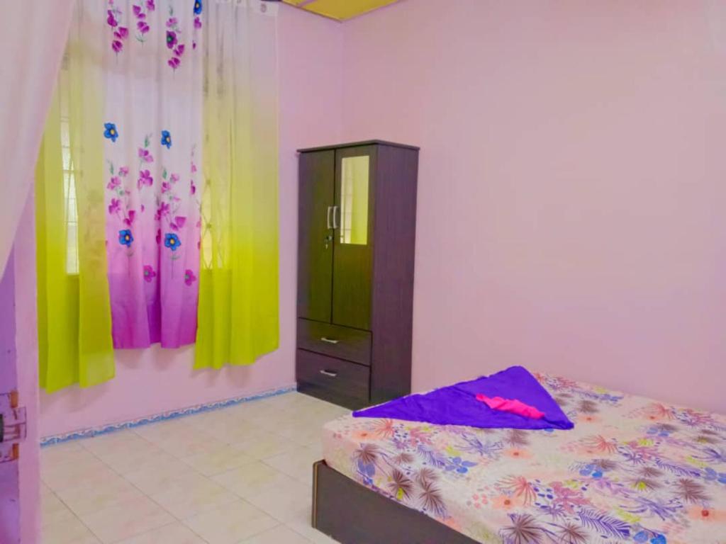 a bedroom with a bed and a dresser with colorful walls at Gooday homestay in Skudai