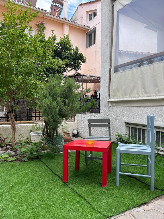 a red table and two chairs in a yard at Maria's maisonette Nea Iraklitsa in Iraklitsa