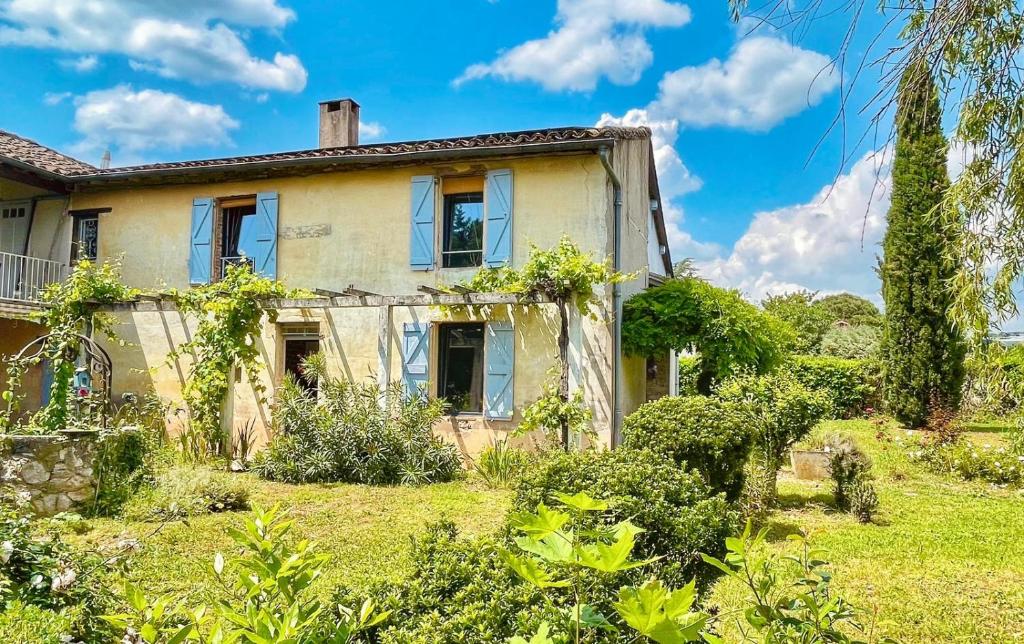 an old house in a yard with bushes at La vieille ferme de Gaillac in Gaillac