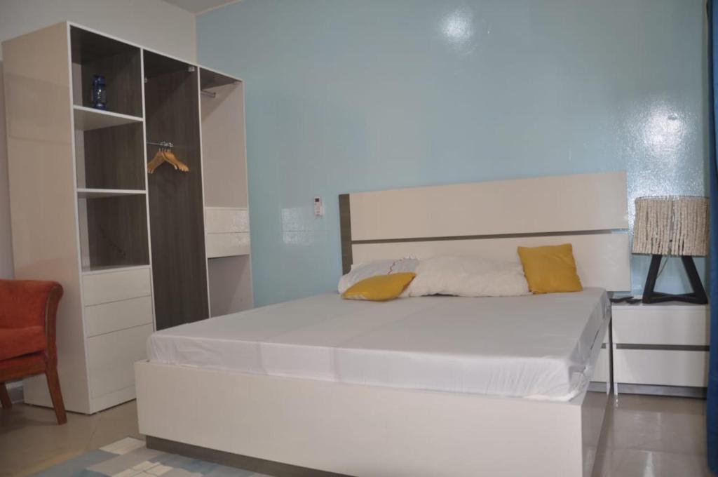 a bedroom with a large white bed with yellow pillows at " Le Nid Douillet ", un fabuleux studio, calme, cosy et bien climatisé au centre de saly in Saly Portudal