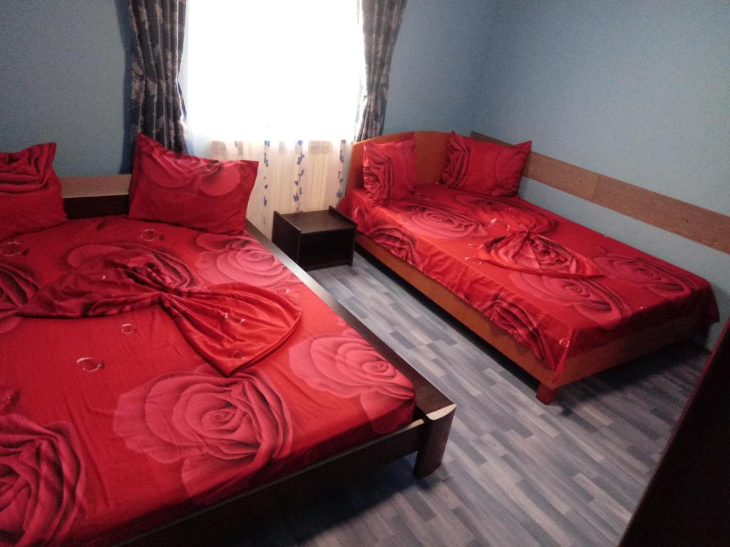 - 2 lits avec des couvertures rouges dans une chambre dans l'établissement Casa de vacanta, à Eforie Nord