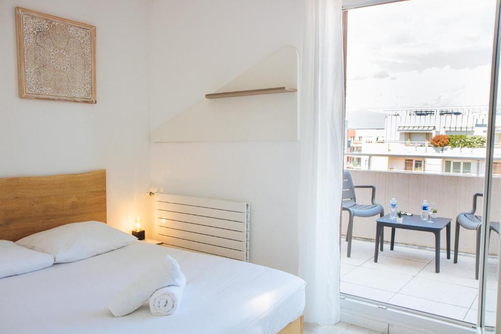 a bedroom with a bed and a balcony with a table and chairs at Twenty Business Flats Nîmes Trigone in Nîmes